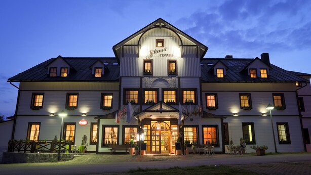 Un grand hôtel à deux étages, avec une enseigne bien visible indiquant « Escaliers » au-dessus de l’entrée.