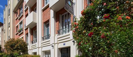Un immeuble résidentiel à plusieurs étages, doté de balcons, d’une façade en briques et d’une enseigne indiquant qu’il s’agit d’une résidence à Paris.