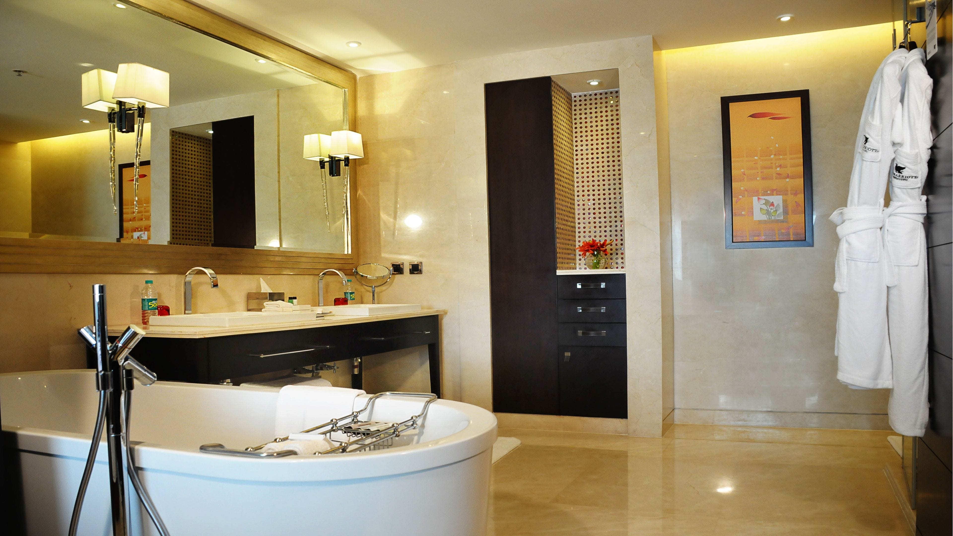 Un baño moderno con bañera independiente, lavamanos dobles y un espejo grande.