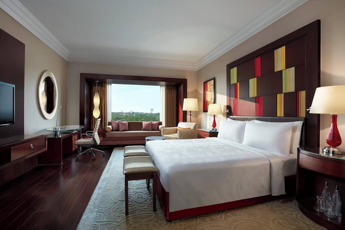 A hotel room with a large bed, a desk, a sofa, and a TV.