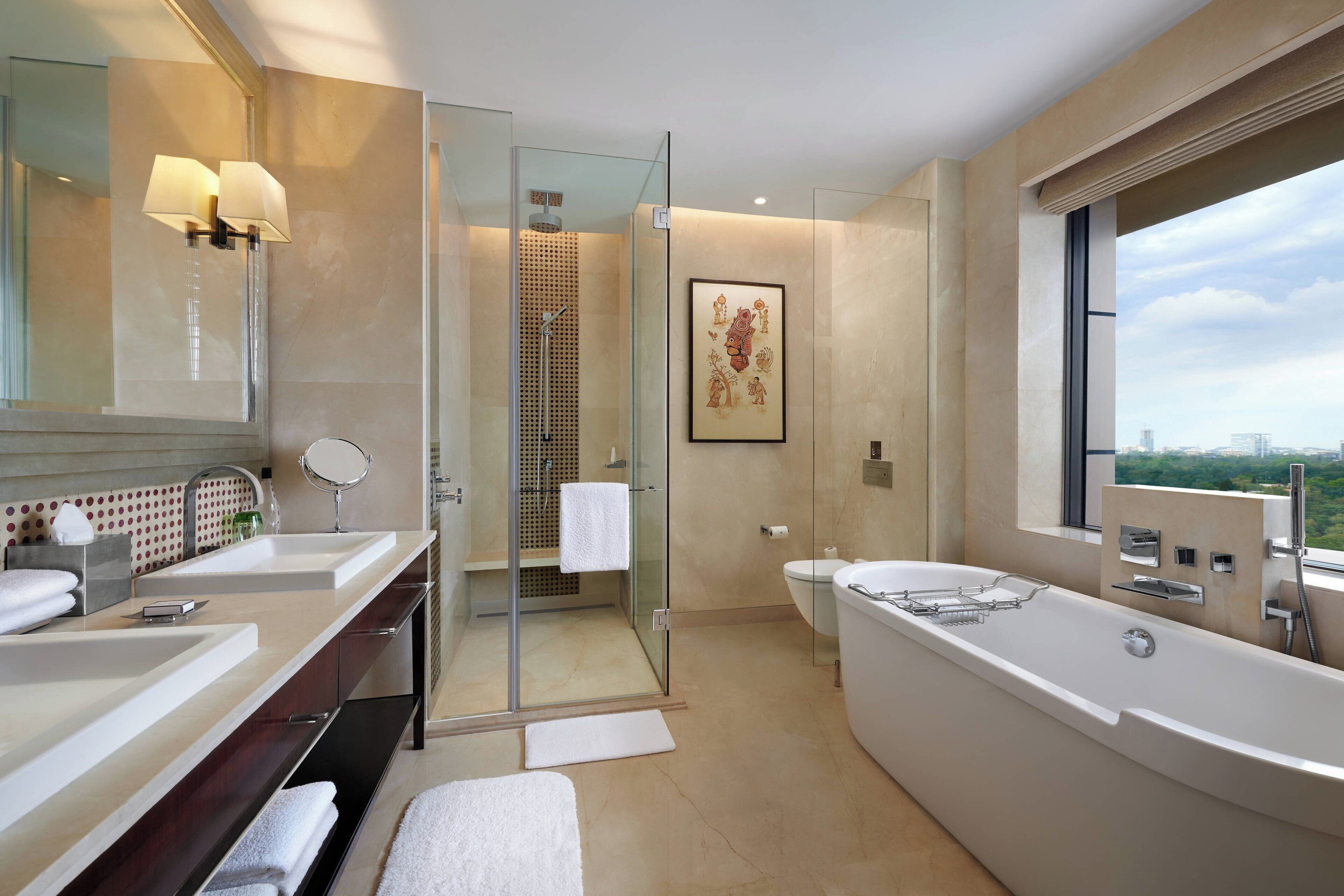 A modern bathroom with two sinks, a large bathtub, a glass-enclosed shower, and a large window offering a city view.