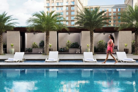 Una piscina al aire libre, sombrillas, sillones reclinables de piscina