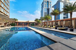 A hotel pool area with multiple lounge chairs and a large rectangular pool. - JW Marriott Hotel Bengaluru (Bengaluru)