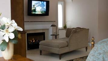 Una sala de estar con un sillón color beige, una chimenea y un televisor montado encima.