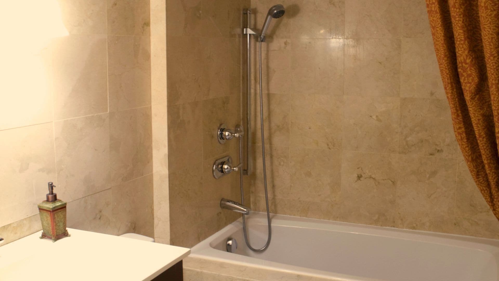 Une salle de bain équipée d’une baignoire, d’une douche avec un pommeau de douche amovible et de toilettes.