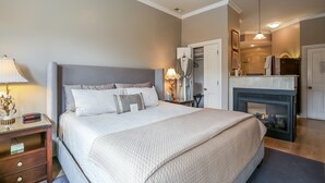 A neatly arranged bedroom with a large bed, bedside lamps, a nightstand, a dresser, and a built-in fireplace. - Harvey House Bed & Breakfast (Oak Park)
