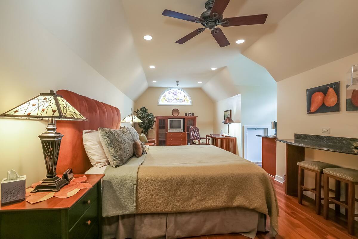 A bedroom with a bed, nightstand, lamp, and a ceiling fan.