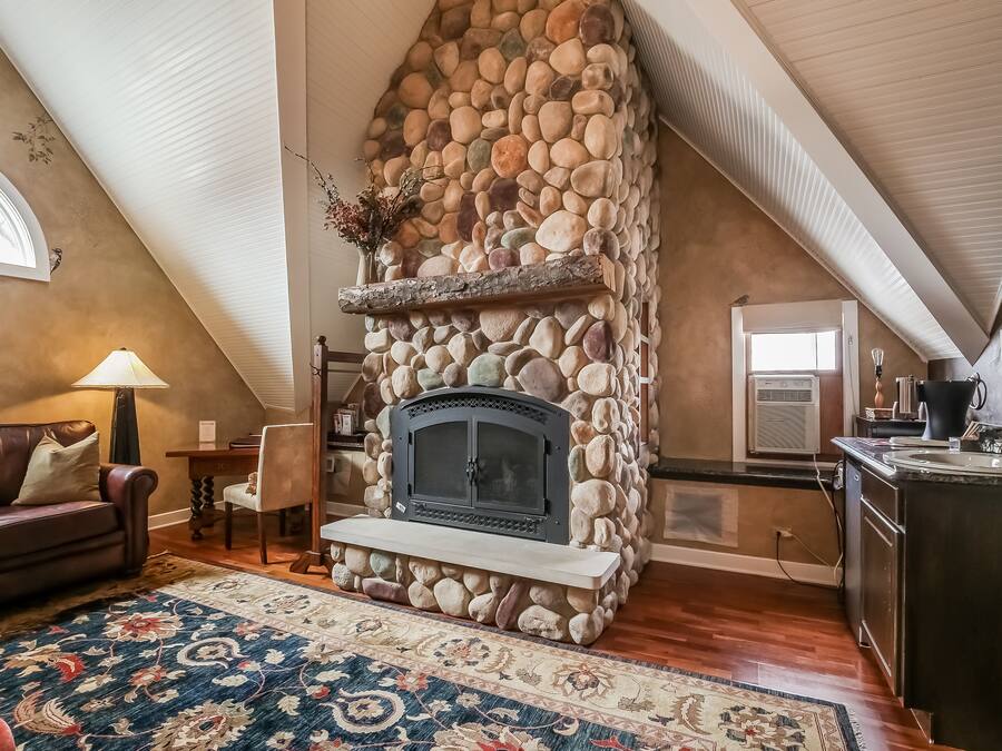 A cozy living room with a stone fireplace, a dining area, and a kitchen.