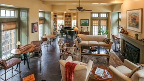 A spacious living room with a fireplace, a piano, and a dining area with a table and chairs. - Harvey House Bed & Breakfast (Oak Park)