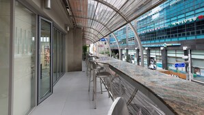 A modern bar area with seating and a view of a commercial building with glass windows and signage. - Metro Hotel (Seoul)