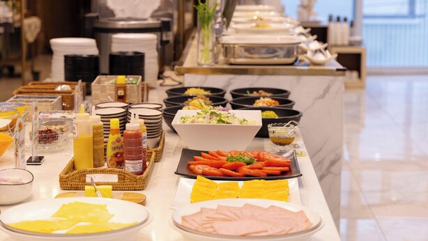 A buffet table with various food items, condiments, and utensils.