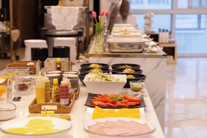 Una mesa de buffet con diversos alimentos, salsas y utensilios.
