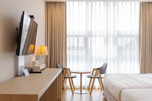 A hotel room with a bed, a desk with a lamp, a chair, and a TV. - Rosana Hotel (Seoul)