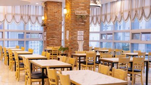 Un restaurante con paredes de ladrillo, ventanas amplias y mesas y sillas de madera.