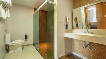 Une salle de bain moderne avec une douche à parois de verre, des toilettes, un lavabo avec un miroir et un porte-serviettes.