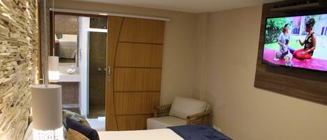 Una habitación de hotel con una cama, televisión, puerta de madera y pared con un diseño texturizado.
