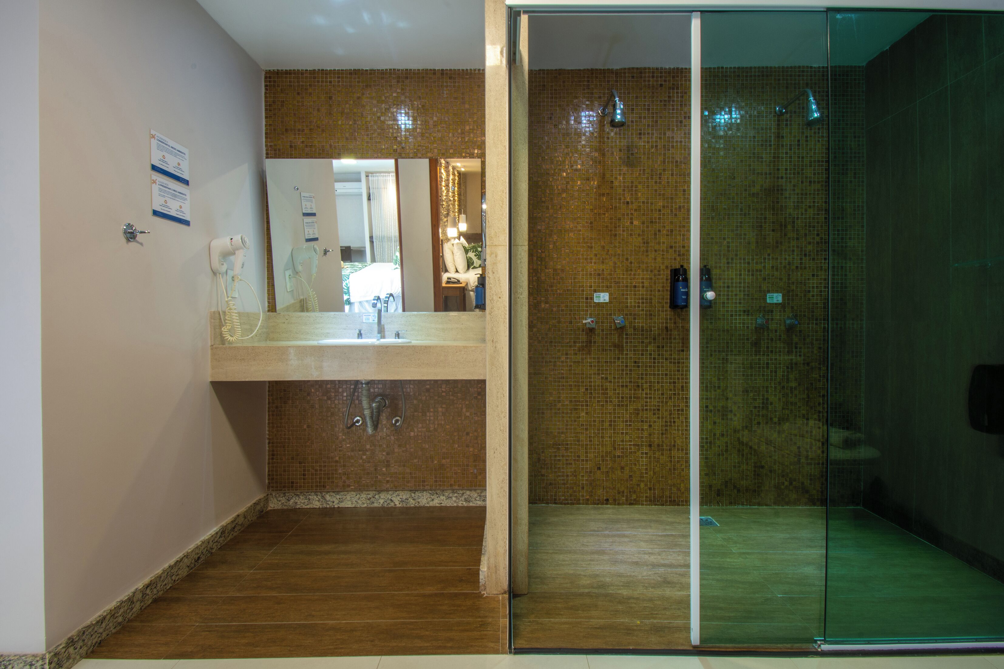 A modern bathroom with a glass shower enclosure, a vanity with a mirror, and a wooden floor.