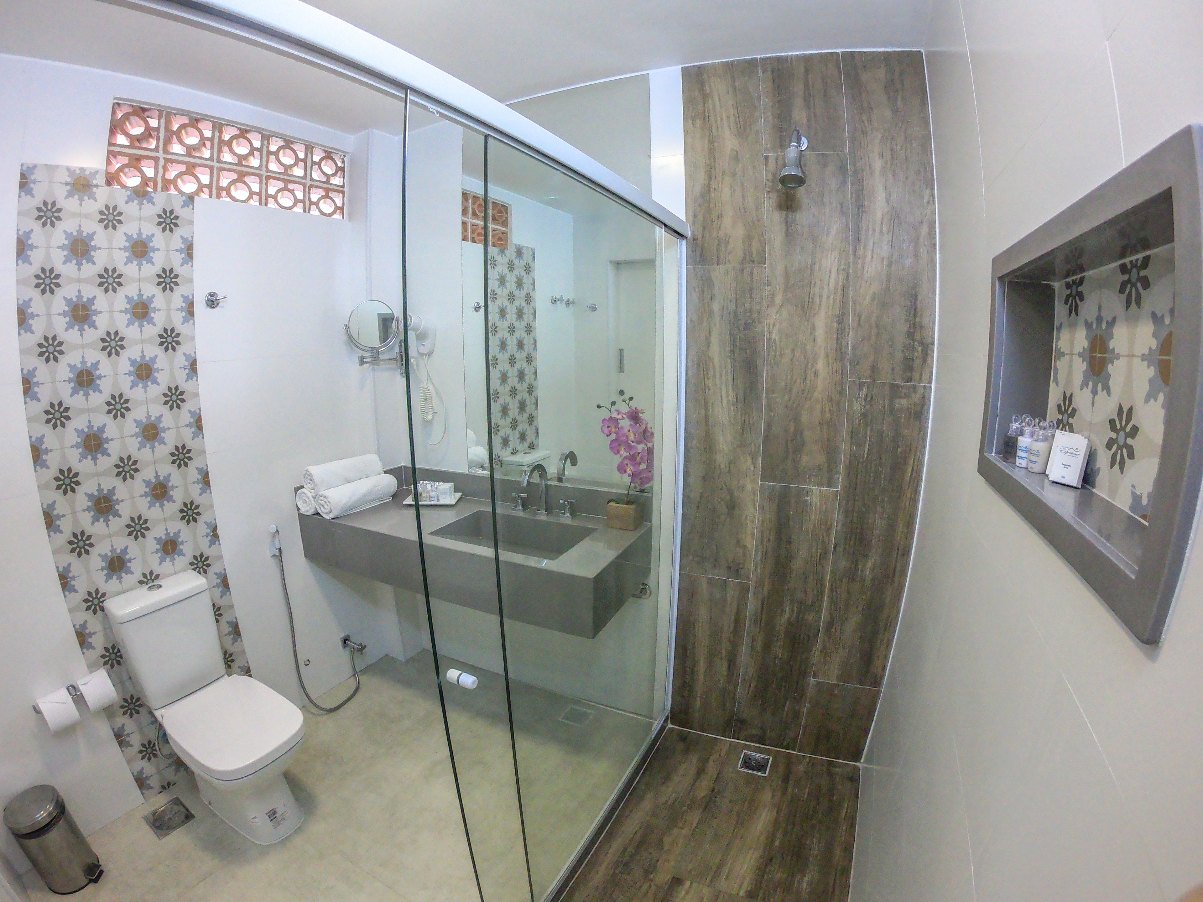 A bathroom with a glass shower enclosure, a toilet, and a sink.