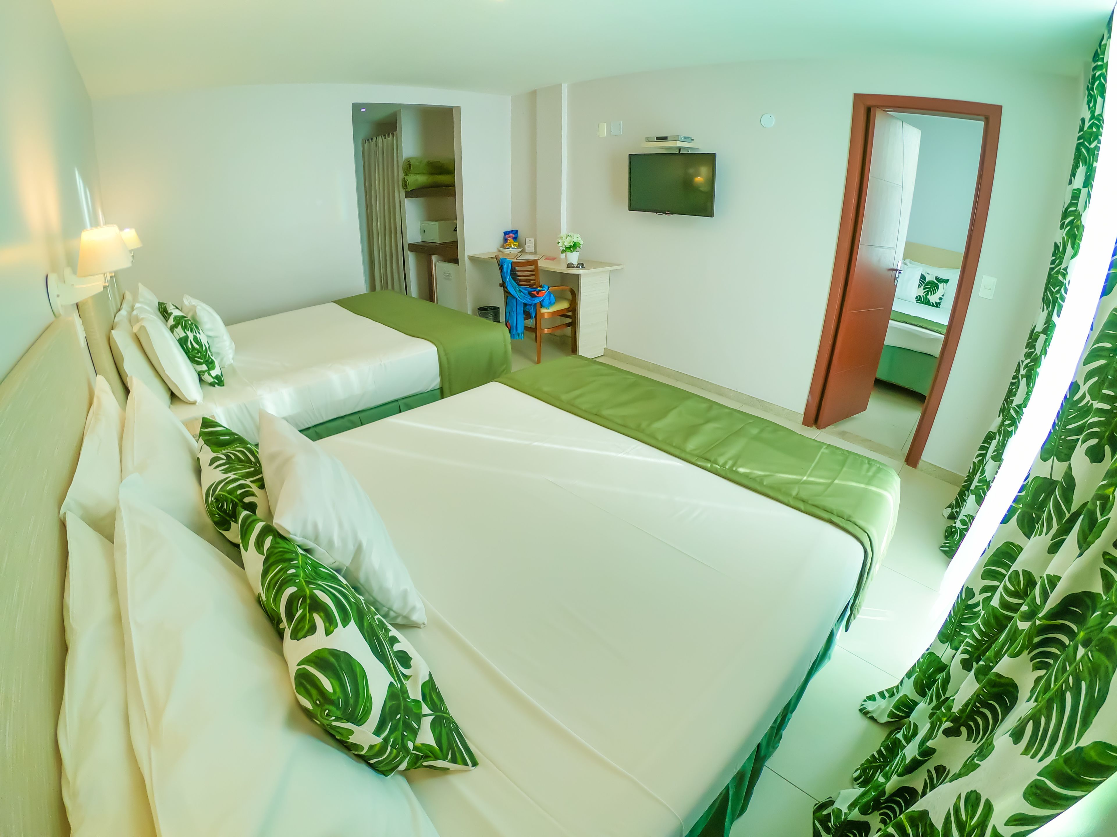 Habitación de hotel con dos camas, un escritorio, un televisor y un espejo.