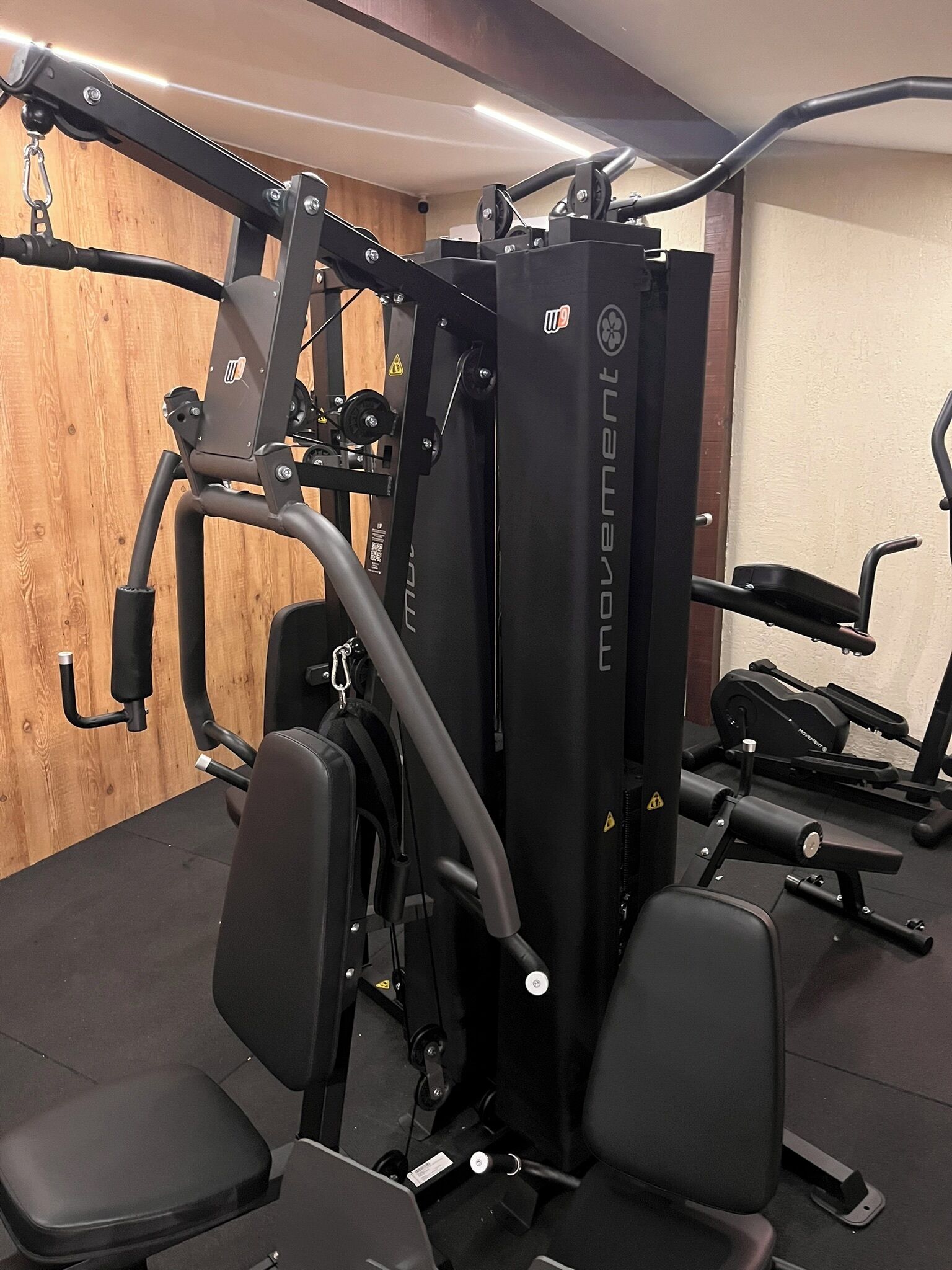 A gym with various exercise equipment, including a cable machine and weight benches.