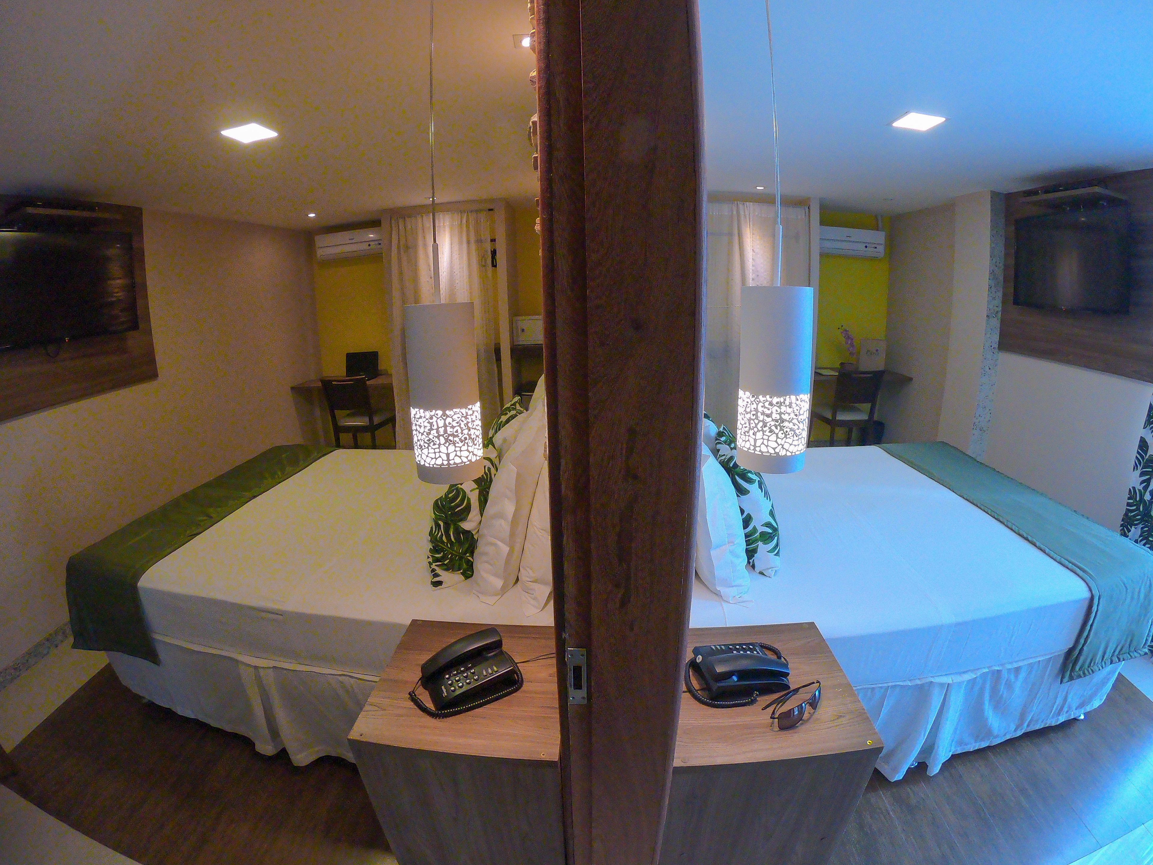 Une chambre d’hôtel avec deux lits, une table de chevet avec un téléphone et une paire de lunettes de soleil, et un bureau avec une chaise.