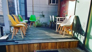 Une terrasse en bois avec un espace salon extérieur, comprenant des chaises et une table, et une fresque murale.