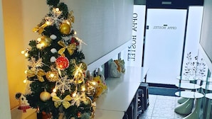 Un couloir d’hôtel orné d’un sapin de Noël décoré, avec un comptoir d’accueil et un aménagement intérieur moderne.