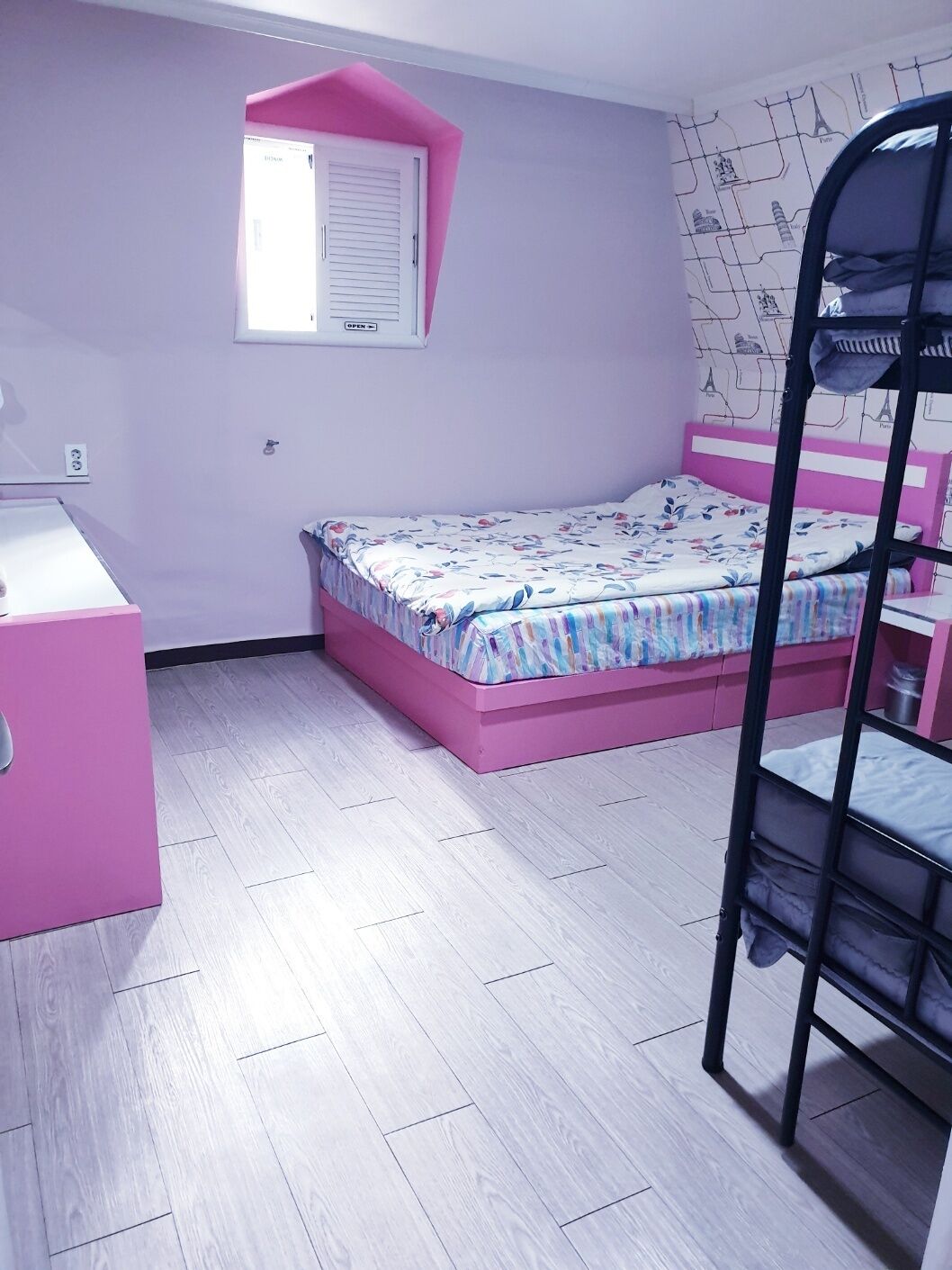 A bedroom with a bunk bed, a desk, and a window with blinds.