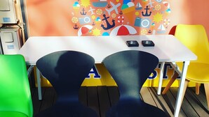 Un coin repas comprenant une table, des chaises et un mur décoré sur le thème de la mer.