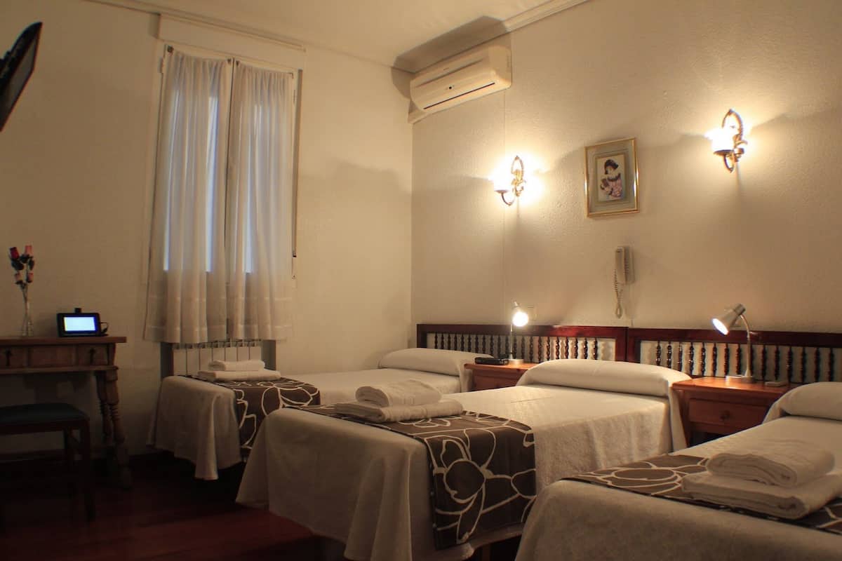 A hotel room with two beds, a desk with a computer, a bedside lamp, and a wall-mounted phone.