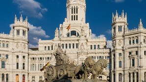 Un edificio imponente con arquitectura detallada, que presenta una torre central y estatuas de leones.