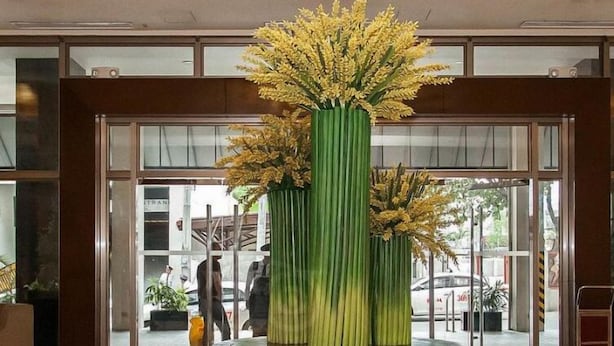 A lobby with a large chandelier, a round table with a green vase of flowers, and large windows with a view of the street. - Mandarin Plaza Hotel (Cebu City)