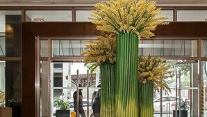 A lobby with a large chandelier, a round table with a vase of yellow flowers, and a glass door entrance. - Mandarin Plaza Hotel (Cebu City)