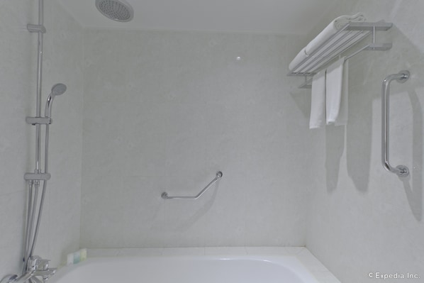 Un bagno con doccia, maniglione di sostegno e porta asciugamani.