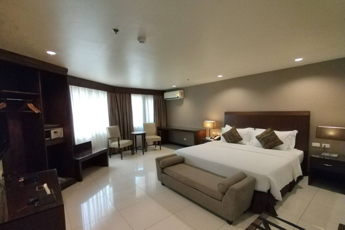 Una habitación de hotel con una cama grande, un sofá, un escritorio y un televisor.
