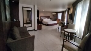 A hotel room with a bed, a sofa, a dining table, and a TV. - Mandarin Plaza Hotel (Cebu City)