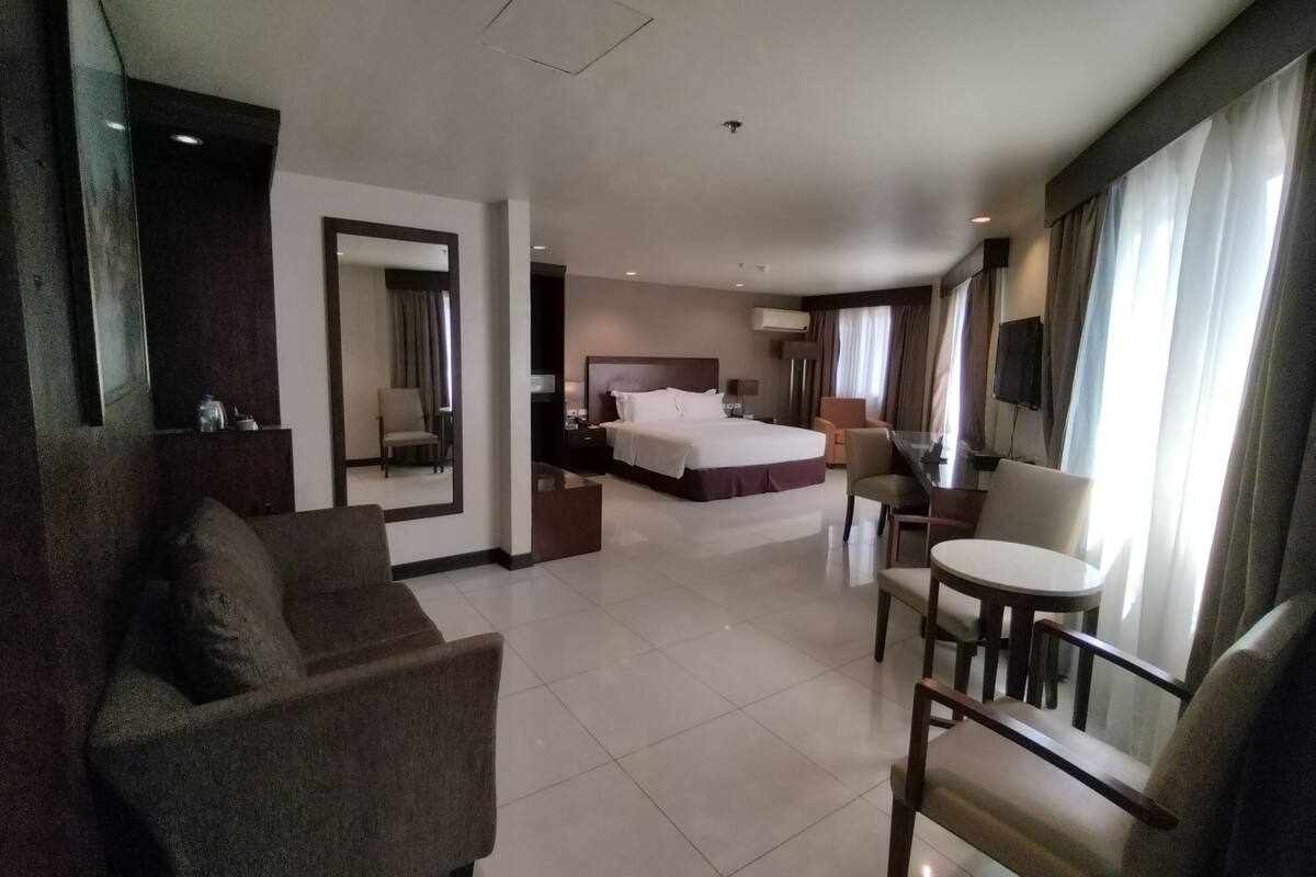 Una habitación de hotel con una cama, un sofá, una mesa de comedor y un televisor.
