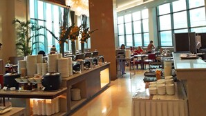 A spacious hotel lobby with a buffet area, large windows, and a high ceiling. - Mandarin Plaza Hotel (Cebu City)