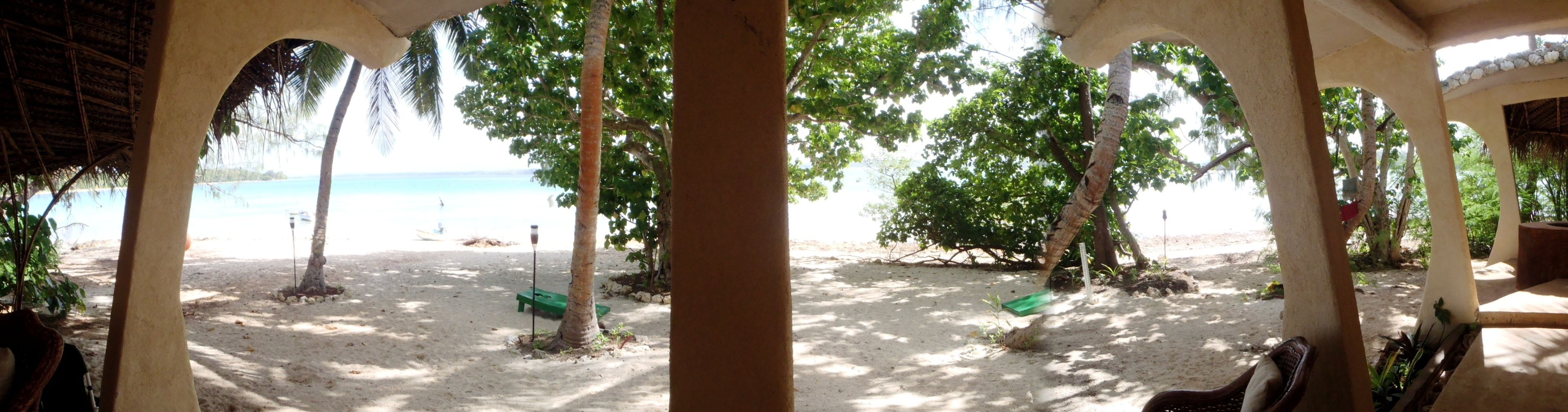A beach view with a covered seating area and a sandy beach.