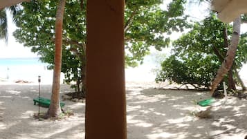 A beach view with a covered seating area and a sandy beach.