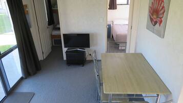 Ein kleines Zimmer mit einem Bett, einem Fernseher und einem Tisch.