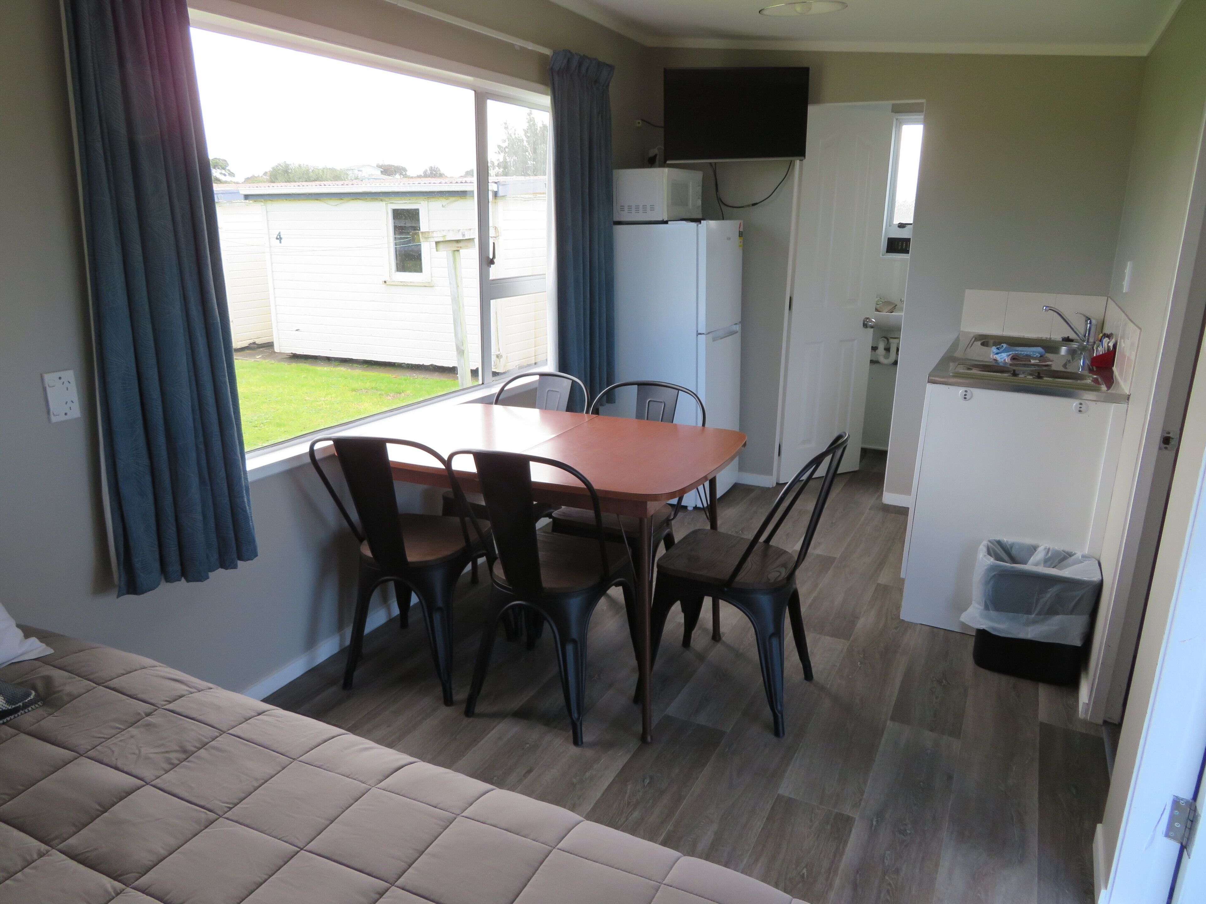 Una cocina compacta con una mesa y sillas, microondas, refrigerador y un lavamanos pequeño.