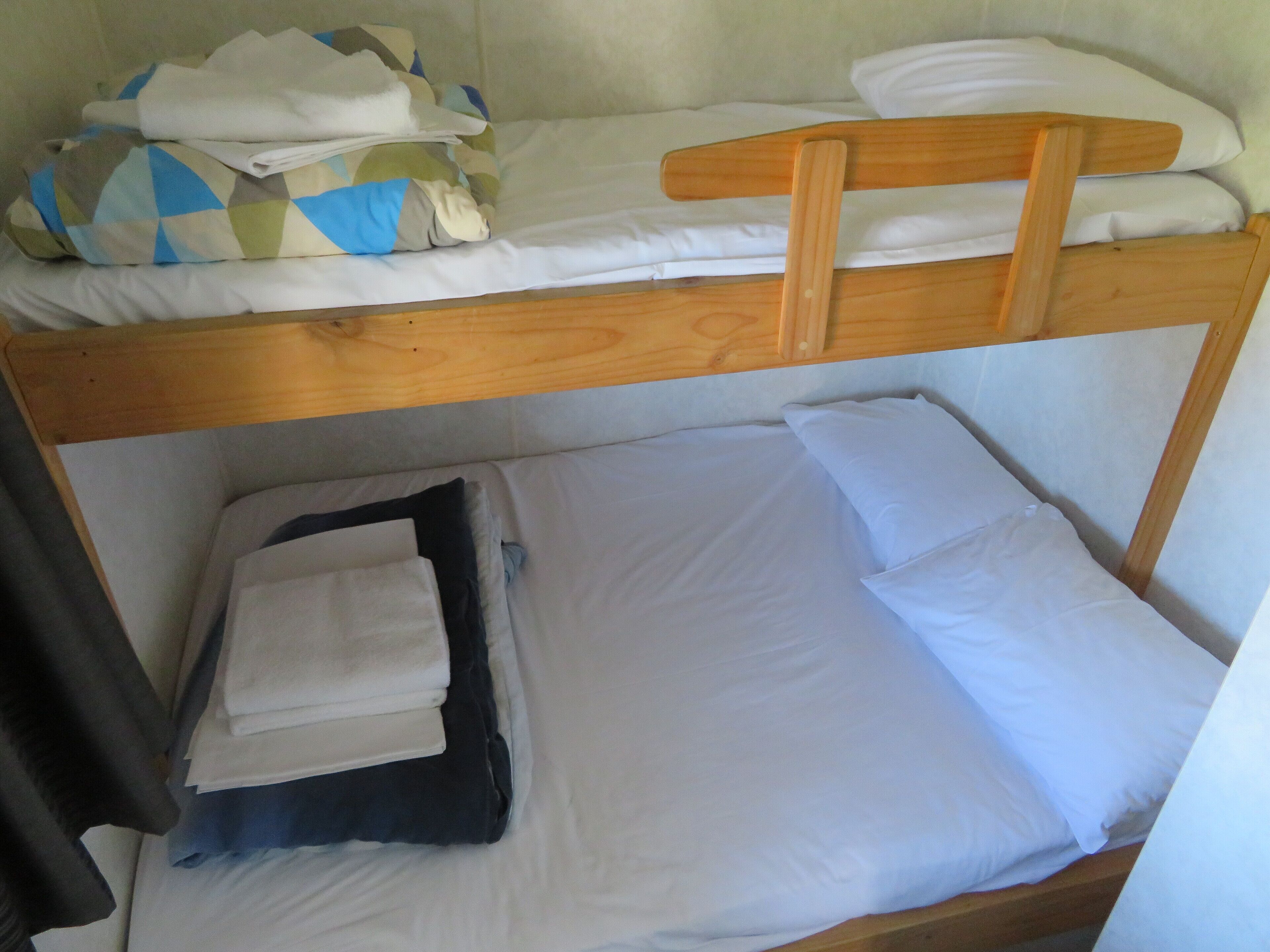 A bunk bed with white bedding and a wooden headboard.