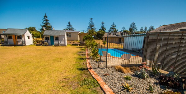 A residential area with a swimming pool, small houses, and a fenced garden area.