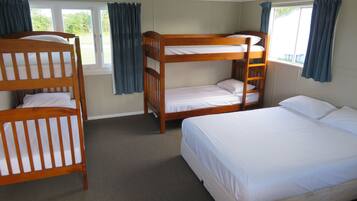 A room with bunk beds, a single bed, and a window with curtains.