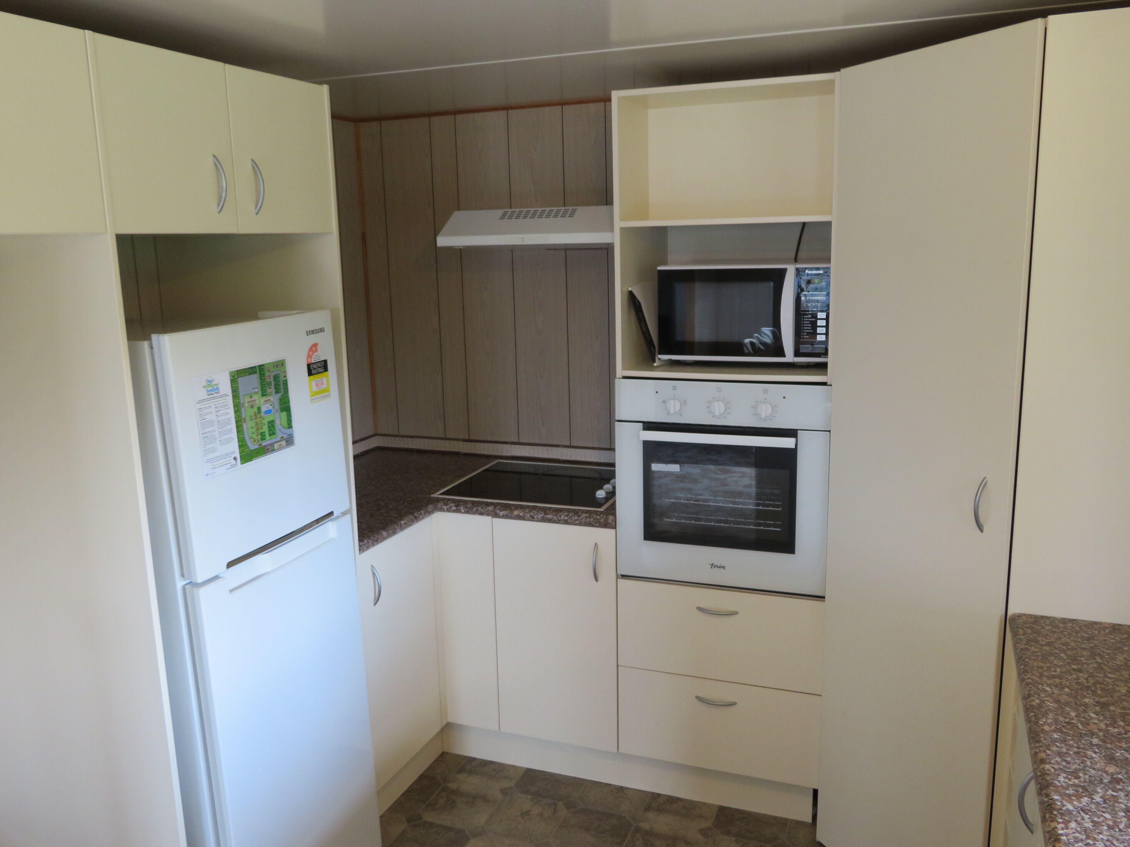A compact kitchen with a white refrigerator, a microwave, and an oven.