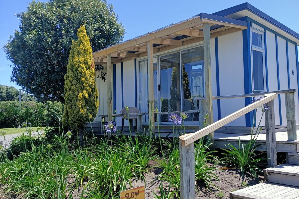 Een gebouw met een blauw-witte gevel, een houten trap die naar een terras leidt, en een bord met de tekst 'VERTRAAG VOOR KINDEREN'.