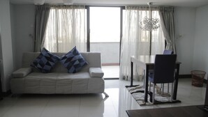 A modern living room with a sofa, a dining table, and a chair.