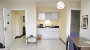 A modern kitchen with white cabinets, a microwave, and a hanging light fixture.