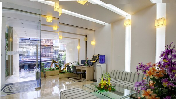 A modern hotel lobby with a glass coffee table, striped sofas, and a reception desk. - Van Mieu 2 Hotel (Hanoi)